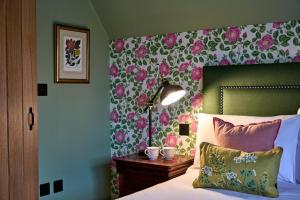 a bedroom with a bed with a flower patterned wall at The Black Horse, Climping in Climping