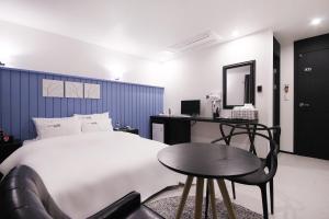 a bedroom with a bed and a table and a chair at XYM Hotel Mundeok in Pohang