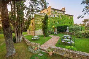 un jardín con mesas y sillas frente a un edificio en Borgo Di Bastia Creti, en Preggio