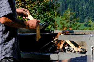 a man holding a spatula next to a fire at Drop In mountain chalet 
