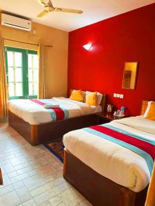 2 łóżka w pokoju z czerwonymi ścianami w obiekcie Horizon Homes - Sauraha Chitwan w mieście Sauraha