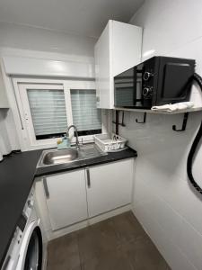 a small kitchen with a sink and a microwave at Apartamento en Zaragoza junto a la Estación Delicias in Zaragoza