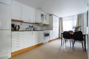 cocina con armarios blancos, mesa y sillas en Sodermalm Hideaway Haven, en Estocolmo