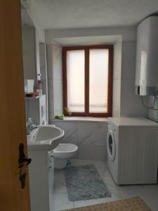 ein weißes Badezimmer mit einem Waschbecken und einer Waschmaschine in der Unterkunft levinja in Izola