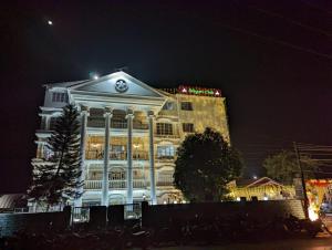 a large white building with a clock on top at night at Siliguri Club in Siliguri