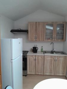 eine Küche mit Holzschränken und einem weißen Kühlschrank in der Unterkunft levinja in Izola
