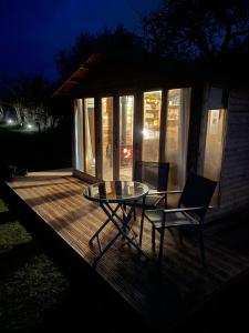 una mesa y una silla en una terraza de madera por la noche en The Deer Hut at Carr House Farm, en Scarborough