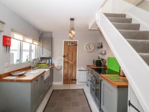 a kitchen with white cabinets and a staircase at Secret Cottage, Southwold in Southwold