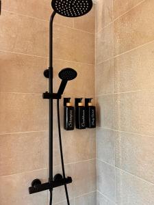 um chuveiro com quatro garrafas pretas numa cabina de duche em The Starlings Country House em Wexford