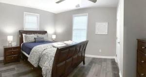 a bedroom with a bed and two windows at The Cottage House on the Blue Mile - Family Friendly, Close to GSU! in Statesboro