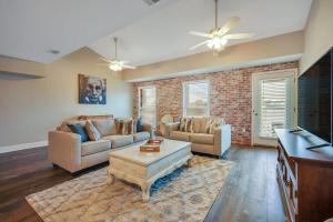 a living room with two couches and a brick wall at Downtown Loft - Above Bull & Barrel & Close to Georgia Southern in Statesboro