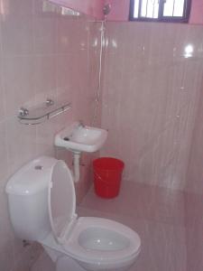 a white bathroom with a toilet and a sink at Pabua's Cottages in Mambajao