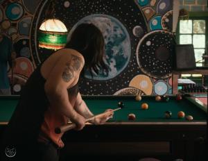 Un uomo con un tatuaggio sul braccio che gioca a biliardo. di Country House Chulumani a Chulumani