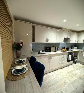 Large Cosy 2 bedroom Apartment in Stevenage SG1 Sleeps 5 في ستيفنيج: مطبخ فيه دواليب بيضاء وطاولة عليها صحون