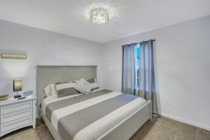 a white bedroom with a bed and a window at GATA Suite - Quiet neighborhood 10 minutes to GSU in Statesboro