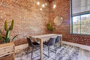 a dining room with a brick wall and a wooden table and chairs at West End Loft - Downtown 5 min walk to River St in Savannah