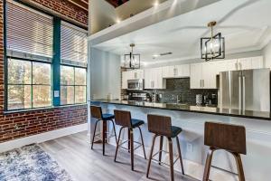 een keuken met een bar met 3 krukken bij West End Loft - Downtown 5 min walk to River St in Savannah