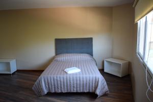 um quarto com uma cama e duas mesas de cabeceira em Duplex Jacaranda I em Ciudad Evita