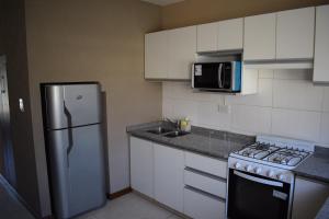 a kitchen with a refrigerator and a stove and a microwave at Duplex Jacaranda I in Ciudad Evita