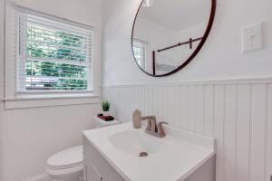 a white bathroom with a sink and a mirror at Mid-Century Bungalow - Blue Mile & Close to GSU in Statesboro +17 photos