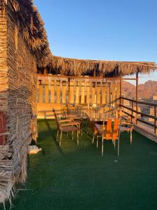 a patio with a table and chairs and a thatch roof at The traditional house in Nizwa