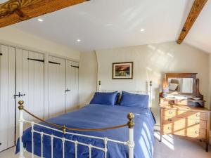 a bedroom with a blue bed and a wooden dresser at 3 Bed in Bedale 81375 in Hackforth