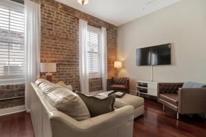 ein Wohnzimmer mit Sofa und Ziegelwand in der Unterkunft Downtown Loft- Steps away from Plant Riverside! in Savannah