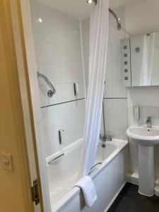 a white bathroom with a tub and a sink at Dashwood Apartments in Banbury