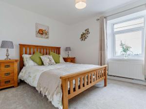 a bedroom with a wooden bed and a window at 4 Bed in Looe 82227 in Saint Cleer