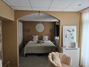 een slaapkamer met een bed, een stoel en een spiegel bij Hotel Restaurant Solskin in Vlissingen