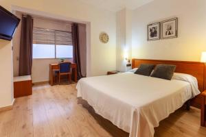 a bedroom with a bed and a desk and a television at Hotel Checkin Travé in Figueres