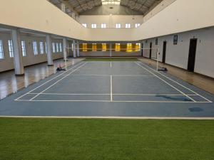 a tennis court in a large building with grass at Siliguri Club in Siliguri