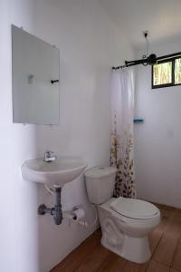 a white bathroom with a toilet and a sink at Paraiso de la sierra in Santa Marta
