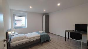 Un dormitorio con una cama, un escritorio y un televisor. en Dammstraße 24-OG-ZV38, en Salzgitter