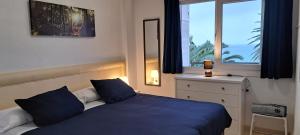 a bedroom with a bed with blue sheets and a window at Acapulco Playa beautiful SeaView in Nerja