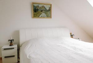 a bedroom with a white bed with a picture on the wall at Ferienwohnung Prof. Dehmer in Zell im Fichtelgebirge