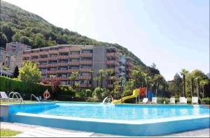 a swimming pool with a slide in front of a building at BellaVista Apartment in Bissone