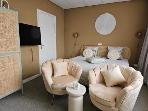 a bedroom with a bed and two chairs and a tv at Hotel Restaurant Solskin in Vlissingen