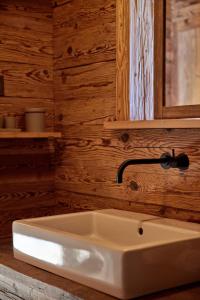 a bathroom with a white sink and a wooden wall at Berghuus Radons in Savognin