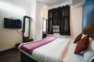 een hotelkamer met een bed en een televisie bij Hotel Vardhmaan Inn in New Delhi