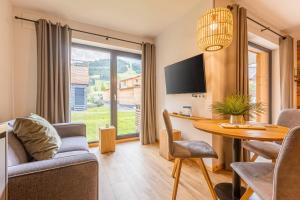a living room with a table and chairs and a tv at Kreischberg Suites by ALPS RESORTS in Sankt Lorenzen ob Murau