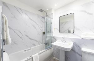 a white bathroom with a sink and a mirror at The Speech House in Coleford