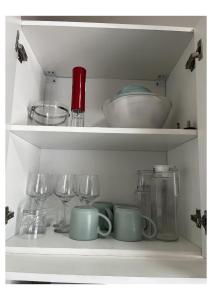 a white shelf with dishes and wine glasses at Chonguile Villa 1 Modern Minimalist in Matola in Matola