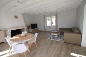 ein Wohnzimmer mit einem Tisch, Stühlen und einem Sofa in der Unterkunft La Maison Bois Carré in Saint-Yzans-de-Médoc