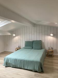 ein Schlafzimmer mit einem großen Bett mit blauer Bettwäsche in der Unterkunft La Maison Bois Carré in Saint-Yzans-de-Médoc