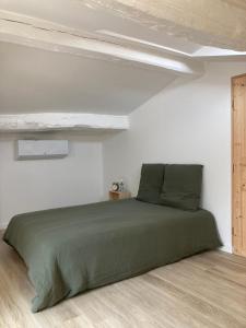 ein Schlafzimmer mit einem grünen Bett in einem weißen Zimmer in der Unterkunft La Maison Bois Carré in Saint-Yzans-de-Médoc