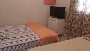 um pequeno quarto com uma cama e uma televisão em Casa compacta em São Caetano do Sul