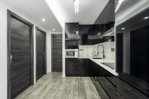 a kitchen with black and white cabinets and a wooden floor at Urbanización jardines del mar in Castillo de Sabinillas