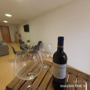 uma garrafa de vinho e dois copos de vinho numa mesa de madeira em Apartamento Calidad - playa - paseos-Servicios em La Garita