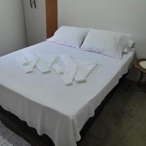 Una cama blanca con almohadas blancas y gafas. en Espaço Bella Ville en Alto Caparao